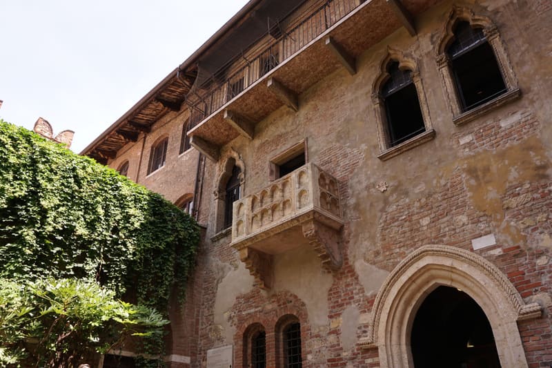 Casa di Giulietta — the medieval Gothic balcony of Juliet's House, viewed from the courtyard with ivy and the Romanesque archway in Verona